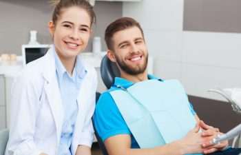 A dentist and a relaxed satisfied man in a dental chair after wisdom tooth removal procedure.