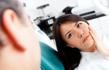 A woman with severe dental pain at emergency dental appointment.