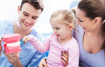 Mother with a little joyful girl who is brushing a dental model during a dental appointment at pediatric dentist in Marietta GA.