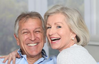 A broadly smiling elderly couple after dental implant restoration Marietta GA