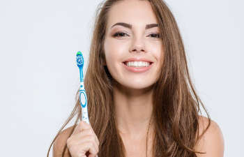 Smiling young woman holding a toothbrush.
