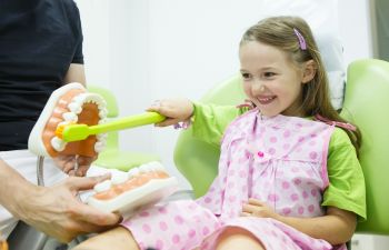 A pre-school girl in a dental chair being educated about oral health at Marietta GA dentistry.