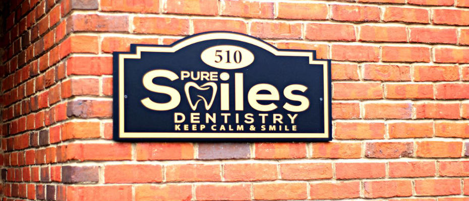 sign on a wall with the pure smiles dentisty logo