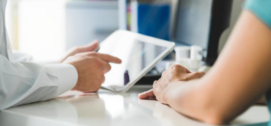 A dentist revising electronic health records while consultation with his pateint.