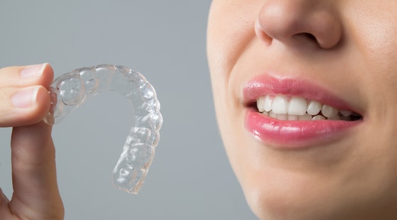 A woman holding an invisalign alligner in her hand