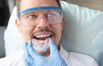 A dentist applying mouthguard on patient's teeth.