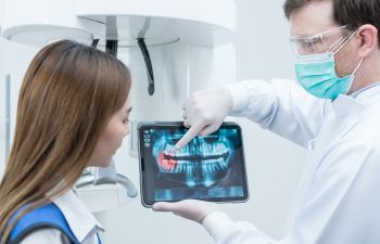 Dentist with dental imaging explaining problem and treatment to the patient.