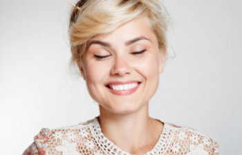 smiling woman in white lace dress with closed eyes