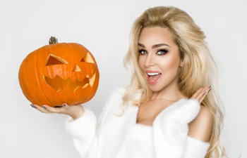 happy beautiful woman holds halloween pumpkin on white background