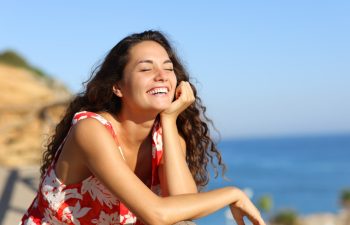 Happy woman in red dress laughing on the beach